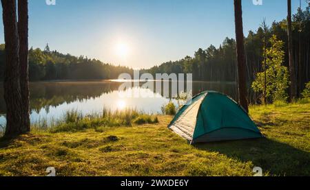 Camping waterproof tent on the shore of lake or river, green forest. Morning sun. Travel and tourism concept. Cinematic shot. Stock Photo