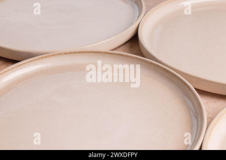 Beige ceramic dinner plates on a brown stone tabletop. Stock Photo
