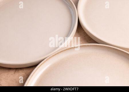 Beige ceramic dinner plates on a brown stone tabletop. Stock Photo