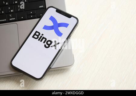 KYIV, UKRAINE - MARCH 15, 2024 BingX logo on iPhone display screen on MacBook panel. Cryptocurrency exchange portal Stock Photo
