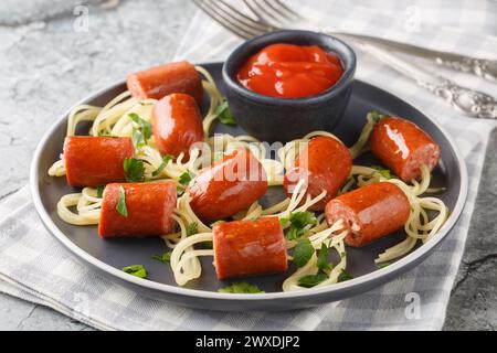 Halloween food spiders funny spaghetti with hot dog and ketchup close-up in a plate on the table. Horizontal Stock Photo