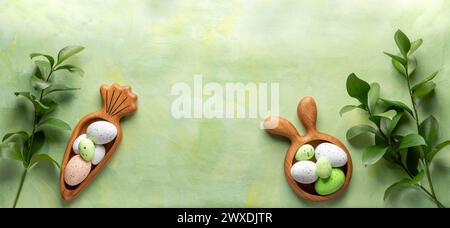 Easter wooden figured plates in form of bunny and carrot with decorative Easter eggs and green Ruskus twigs on textured green yellow background. Creat Stock Photo