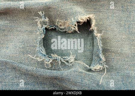 Hole in denim fabric. Ripped jeans Stock Photo