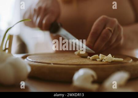 cooking, slicing garlic cloves on wooden cutting board Stock Photo