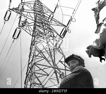 Socialist Republic of Romania in the 1970s. Workers on a high voltage electric pole. Stock Photo