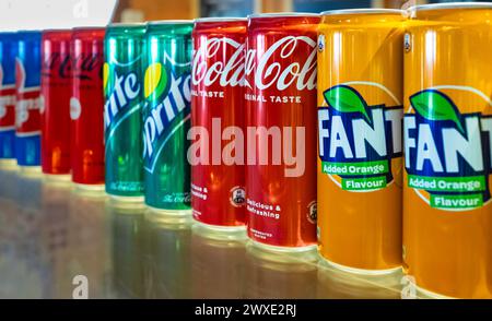 Coca-Cola Fanta Sprite products lemonade soft drinks in cans in a row on the shelf of the shop. Group of most popular brands of soda drinks in aluminu Stock Photo