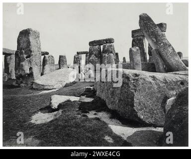 An unknown man sitting on a stone at Stonehenge. Monochrome photograph by photographer Francis Frith. 1864 - 1898. Stonehenge is a prehistoric monument on Salisbury Plain in Wiltshire, England, two miles west of Amesbury. It consists of an outer ring of vertical sarsen standing stones, each around 13 feet high, seven feet wide, and weighing around 25 tons, topped by connecting horizontal lintel stones  Bronze Age Britain Stock Photo