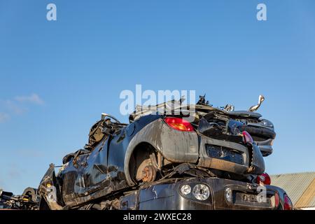 Stacked cars at a junkyard in the South-Holland village of Lisse in the Netherlands. On a blue sky. Stock Photo