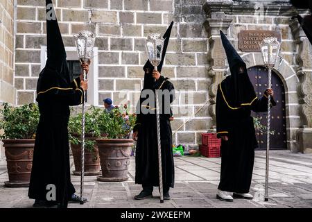 Antigua, Guatemala. 29th Mar, 2024. A confraternity of penitents, wearing capirote hats, wait outside the Escuela de Cristo church for the start of the Senor Sepultado Good Friday procession during Semana Santa, March 29, 2024 in Antigua, Guatemala. The opulent procession is one of the largest in the world involving thousands of devotees and lasting 12-hours. Credit: Richard Ellis/Richard Ellis/Alamy Live News Stock Photo