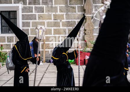 Antigua, Guatemala. 29th Mar, 2024. A confraternity of penitents, wearing capirote hats, wait outside the Escuela de Cristo church for the start of the Senor Sepultado Good Friday procession during Semana Santa, March 29, 2024 in Antigua, Guatemala. The opulent procession is one of the largest in the world involving thousands of devotees and lasting 12-hours. Credit: Richard Ellis/Richard Ellis/Alamy Live News Stock Photo