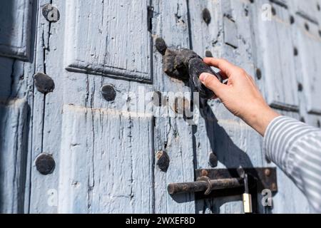 Closeup view of the hand of an unrecognizable man knocking on the wooden old door, male visitor standing in entrance, guest man wants to come in, he i Stock Photo