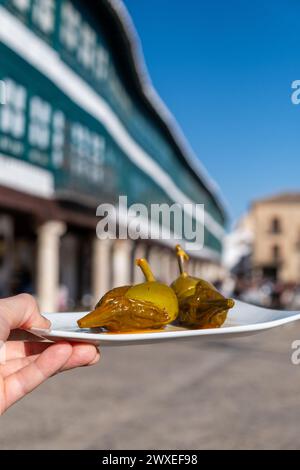 Detail of a man's hand shows a typical dish of Almagro, in Castilla la Mancha, of eggplants called berenjenas de Almagro with the main square out of Stock Photo