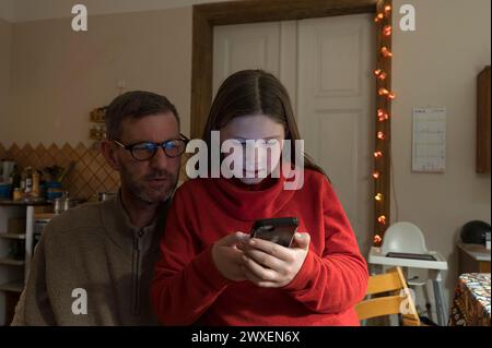 Girl, 10 years, on mobile phone, father watching, Mecklenurg-Vorpommern, Germany Stock Photo