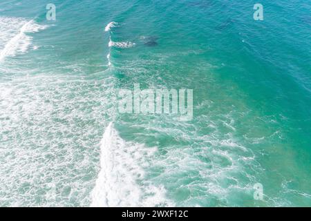 foam of waves breaking near the beach, turquoise sea seen from a drone. Aerial view Stock Photo