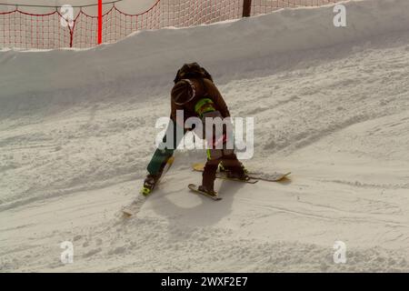 OBERSTDORF, GERMANY - FEBRUARY 24, 2024: An adult man, standing on skis, teaches a small child to ski Stock Photo