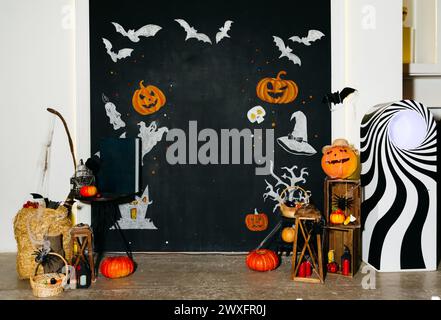 A festive Halloween scene with carved pumpkins, bats on a black wall, and themed decorations creating a spooky atmosphere. Stock Photo