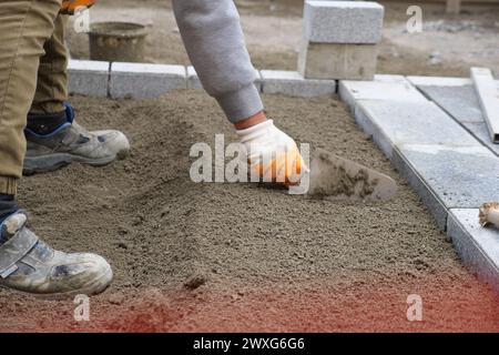 a worker laying concrete bricks on each other for building a new sidewalk Stock Photo