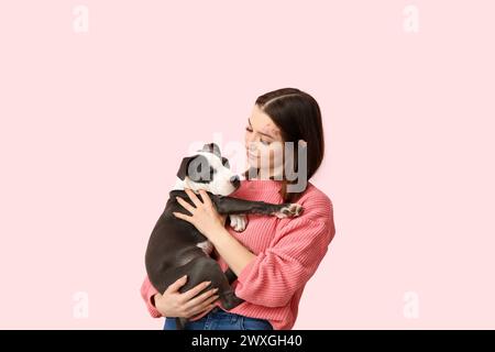 Beautiful young woman with cute staffordshire terrier puppy on pink background Stock Photo