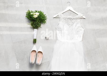 Wedding composition with dress, shoes, bouquet and ring box on grey tiles background Stock Photo