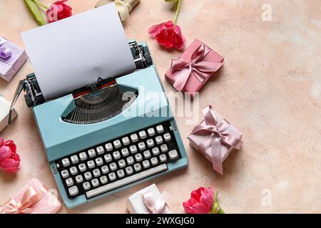 Composition with typewriter for Women's Day, gift boxes and tulips on pink background Stock Photo