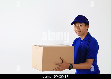 Delivery Man in Blue Uniform Send Package in Cardboard Box. Male Employee in Cap T-shirt Print Working as Courier Dealer. Service Concept. On White Ba Stock Photo