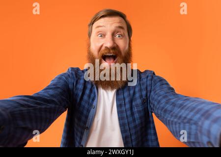 Excited Man With Red Beard Shouting Spreading Hands, Orange Background Stock Photo