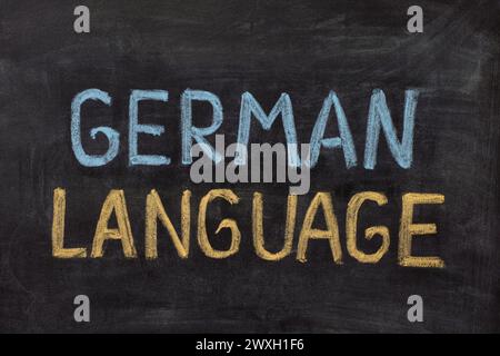 The words German Language handwritten with chalk on a blackboard. Stock Photo