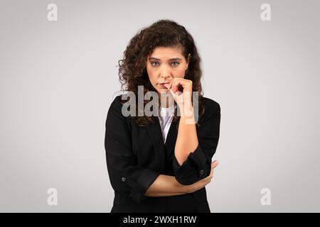 Curly-haired woman pondering with hand on chin Stock Photo