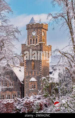 The clock tower of Fort Augustus Abbey (now holiday accommodation) through snow-covered trees Stock Photo