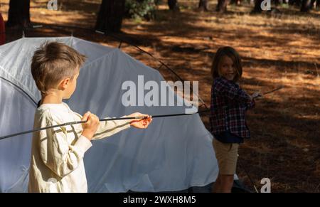 Two children pitching a tent in the woods Stock Photo