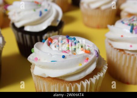 A variety of colorful cupcakes with frosting and sprinkles on a table Stock Photo