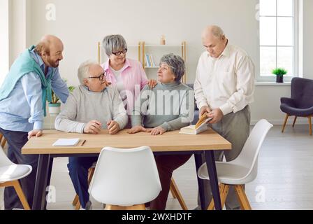 Group of senior people men and women talking in nursing home sitting at the table. Stock Photo