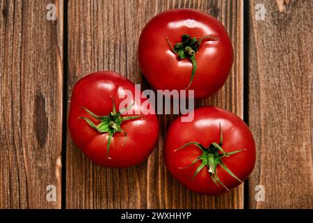Red ripe tomatoes on a dark wooden background. Harvesting of fresh tomatoes. View from above. Stock Photo
