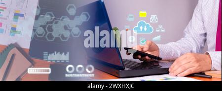 businessman in office saves his business data securely in the cloud from his laptop and smartphone Stock Photo