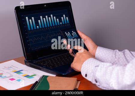 businessman analyzes business graphs using his smartphone and laptop. secure and accurate data Stock Photo