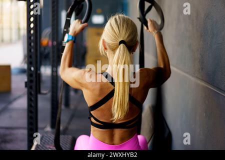 Strong young woman doing exercises with gymnastic rings in fitness club Stock Photo