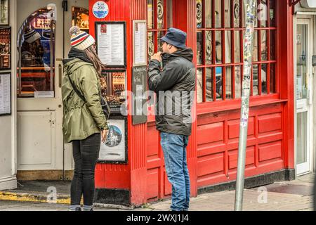 Young couple studying outside menu in front of Irish pub / restaurant. Dublin. Ireland. Stock Photo