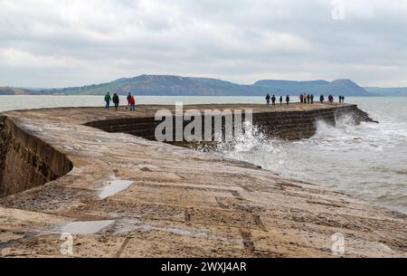 Lyme Regis, Dorset, UK. 31st March 2024. UK weather: cool day with an occasional glimpse of sunshine at Lyme Regis on Easter Sunday. Visitors walk along the Cobb. Credit: Carolyn Jenkins/Alamy Live News Stock Photo