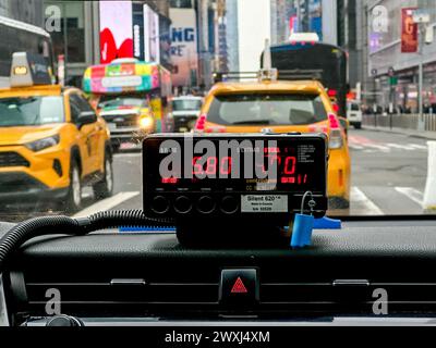 NEW YORK, NY, USA - MARCH 27, 2024: The view from the backseat of a taxi shows a vibrant urban scene with yellow cab ahead  with fare meter Stock Photo