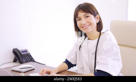 Female doctor using computer and smiling at camera Stock Photo