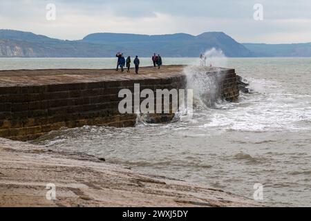 Lyme Regis, Dorset, UK. 31st March 2024. UK weather: cool day with an occasional glimpse of sunshine at Lyme Regis on Easter Sunday. Visitors walk along the Cobb. Credit: Carolyn Jenkins/Alamy Live News Stock Photo