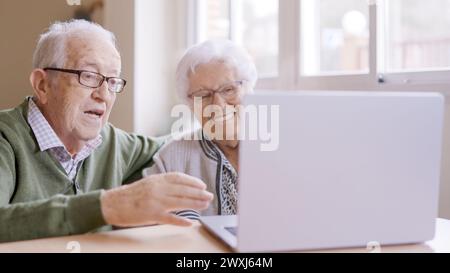 Senior people talking during online meeting using laptop in geriatric Stock Photo