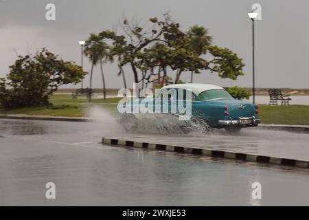 126 Old blue-white almendron car -Buick classic from 1953- drives down Jovellar and Marina Streets in the hard rain of a tropical storm. Havana-Cuba. Stock Photo