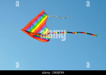 Colorful kite flying in clear sky Stock Photo