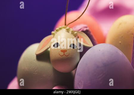 Painted Easter eggs in a pink box on blue background. Cute toy rabbit. Pastel decor for traditional spring holiday. Festive springtime decoration. Stock Photo
