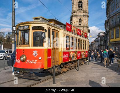 The iconic red tram number 18 pauses in front of the Clerigos Church Tower, Porto, Portugal Stock Photo