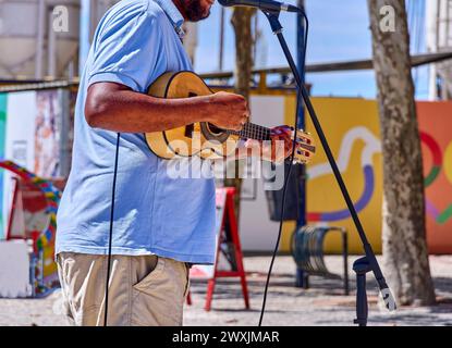 A musician plays guitar, captured mid-performance outdoors. Stock Photo