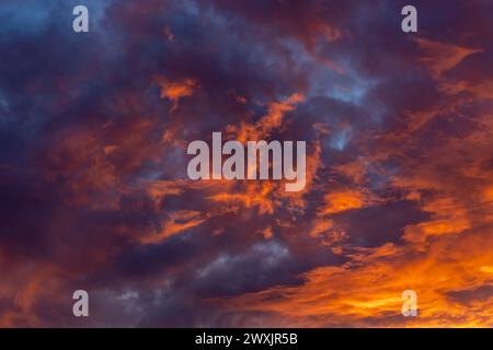 Dramatic fiery bloody sky with orange, red and purple fluffy clouds at sunset Stock Photo