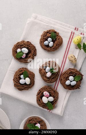 Easter chocolate cookies in the shape of Nests with sweet eggs on white napkin with mint leaves. top view Stock Photo