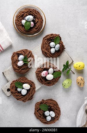 Easter chocolate cookies in the shape of Nests with sweet eggs with mint leaves on light table. top view. Stock Photo